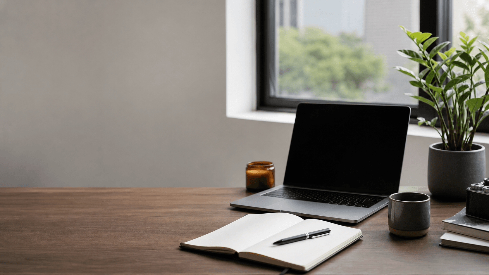 Desk with laptop, notebook, and window light